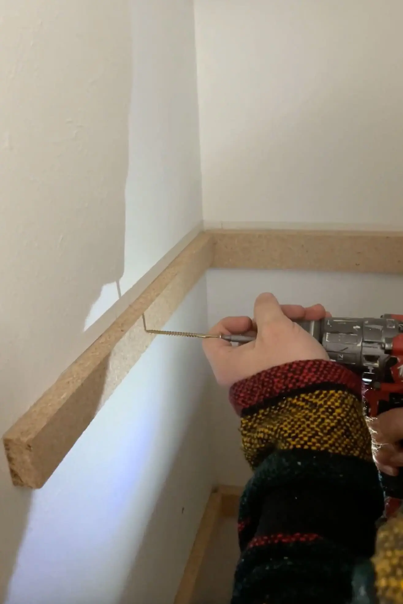 A close-up of a DIY closet shelves project, securing wooden shelf supports with screws for a sturdy and custom-built storage solution.